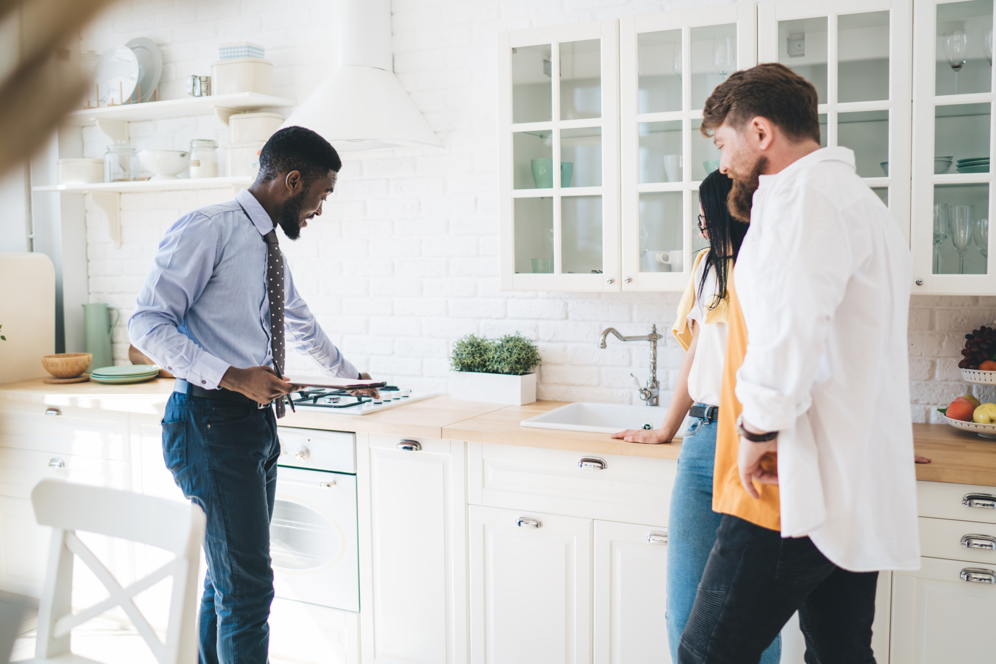 Realtor Presenting New Kitchen To Young Buyers